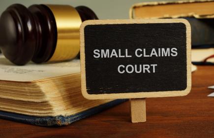 small sign with the words small claims + courts with gavel in the background