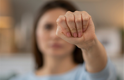 shows a signal to ask for help during domestic violence, known as the "Signal for Help" gesture, where the thumb is tucked into the palm and the fingers are closed over it. 